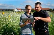 2 Personen schauen auf Tablet auf einem Feld 